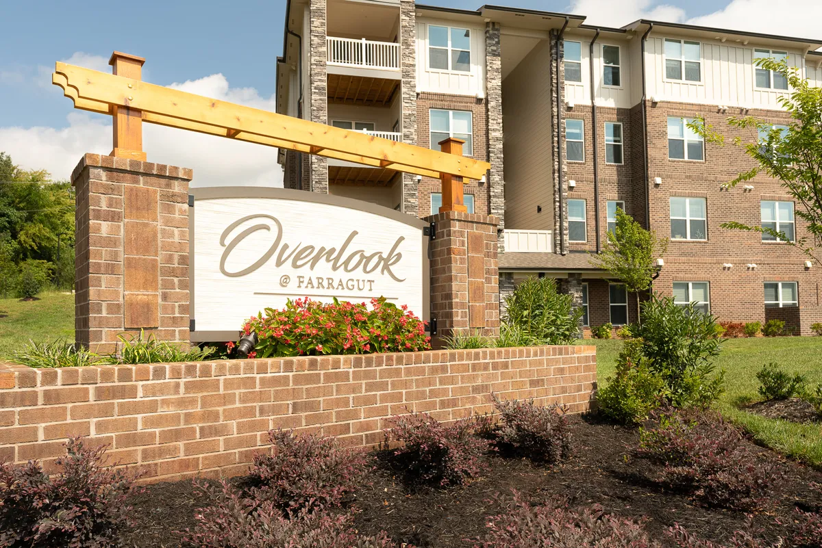 This image showcases the Overlook at Farragut sign framed by meticulously landscaped flower beds and the sleek building facade. The scene is bathed in natural light, creating an inviting and serene first impression of the community.