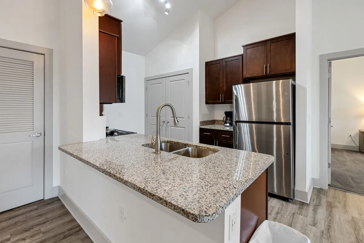 A welcoming kitchen with sleek granite countertops, stainless steel appliances, and warm wood cabinetry. The open layout provides plenty of space for cooking and socializing, with natural light enhancing the inviting atmosphere.