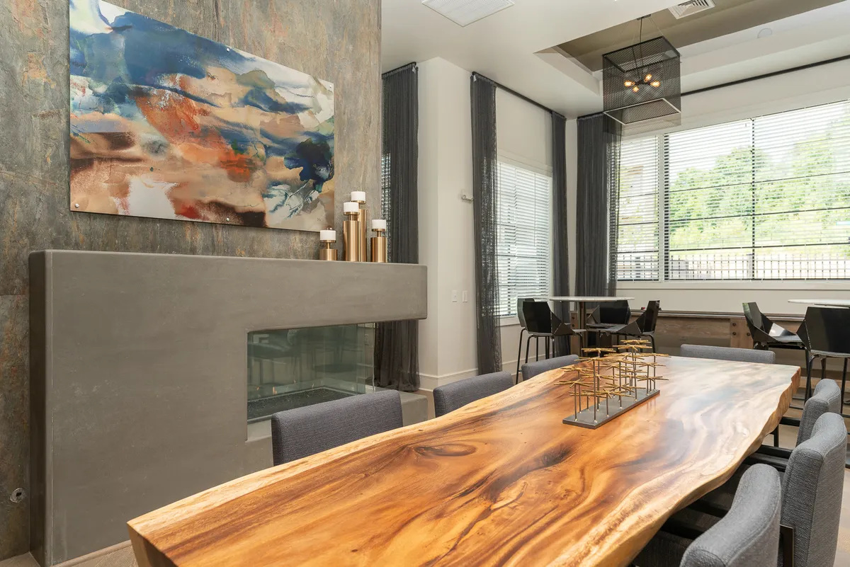 A sophisticated dining room featuring a large wooden dining table, abstract art on the wall, and a modern fireplace. The space radiates warmth and is designed for both intimate dinners and larger gatherings.